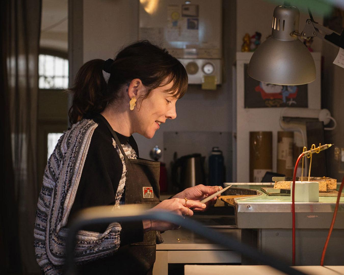 Creative mom artisan carefully crafting jewelry at her workshop bench, exemplifying skill and dedication