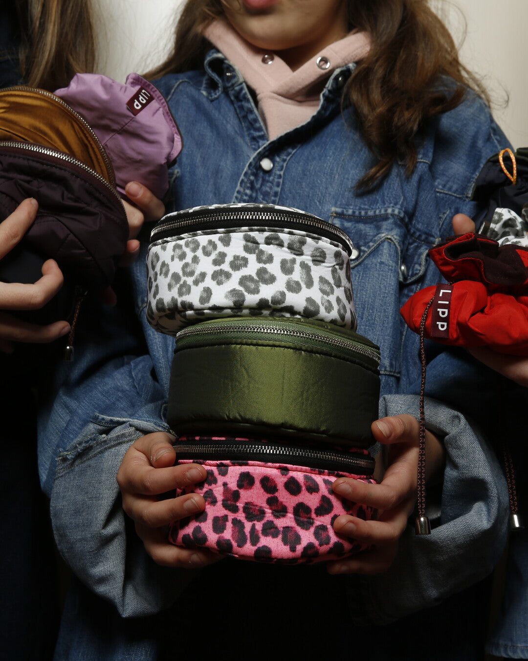 Person holding a stack of colorful pouches with leopard print patterns.
