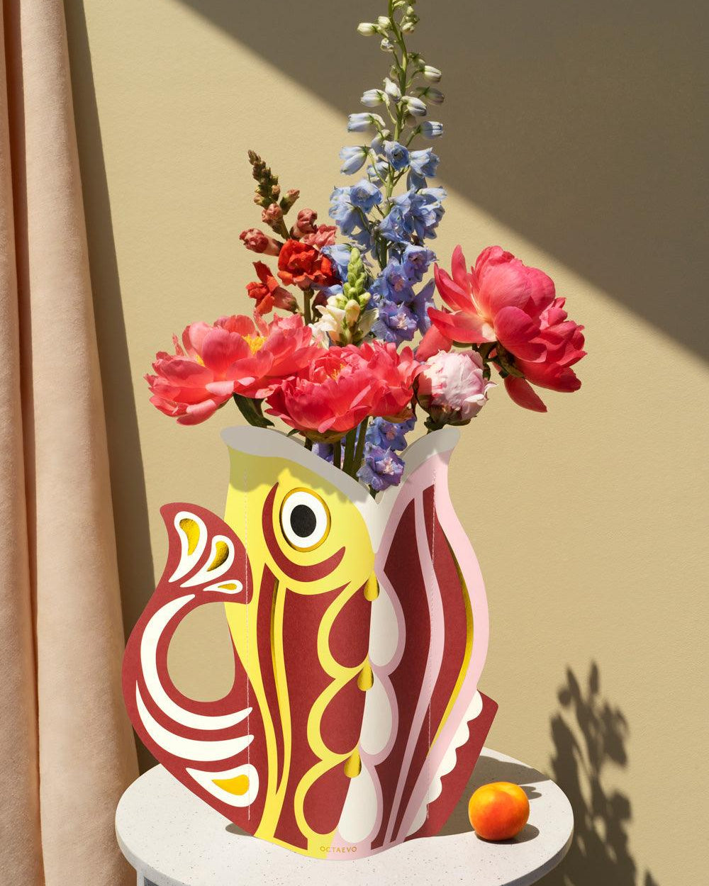 Decorative red OCTAEVO fish-shaped vase with colorful flowers.