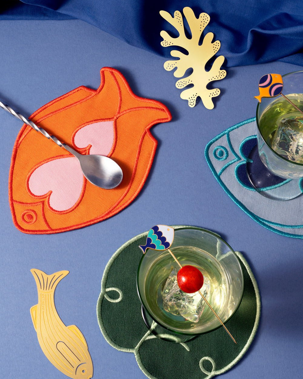 Colorful cocktails on Octaevo Fish Splash Coasters (Set of 4), featuring fish and coral, atop a vibrant blue surface.