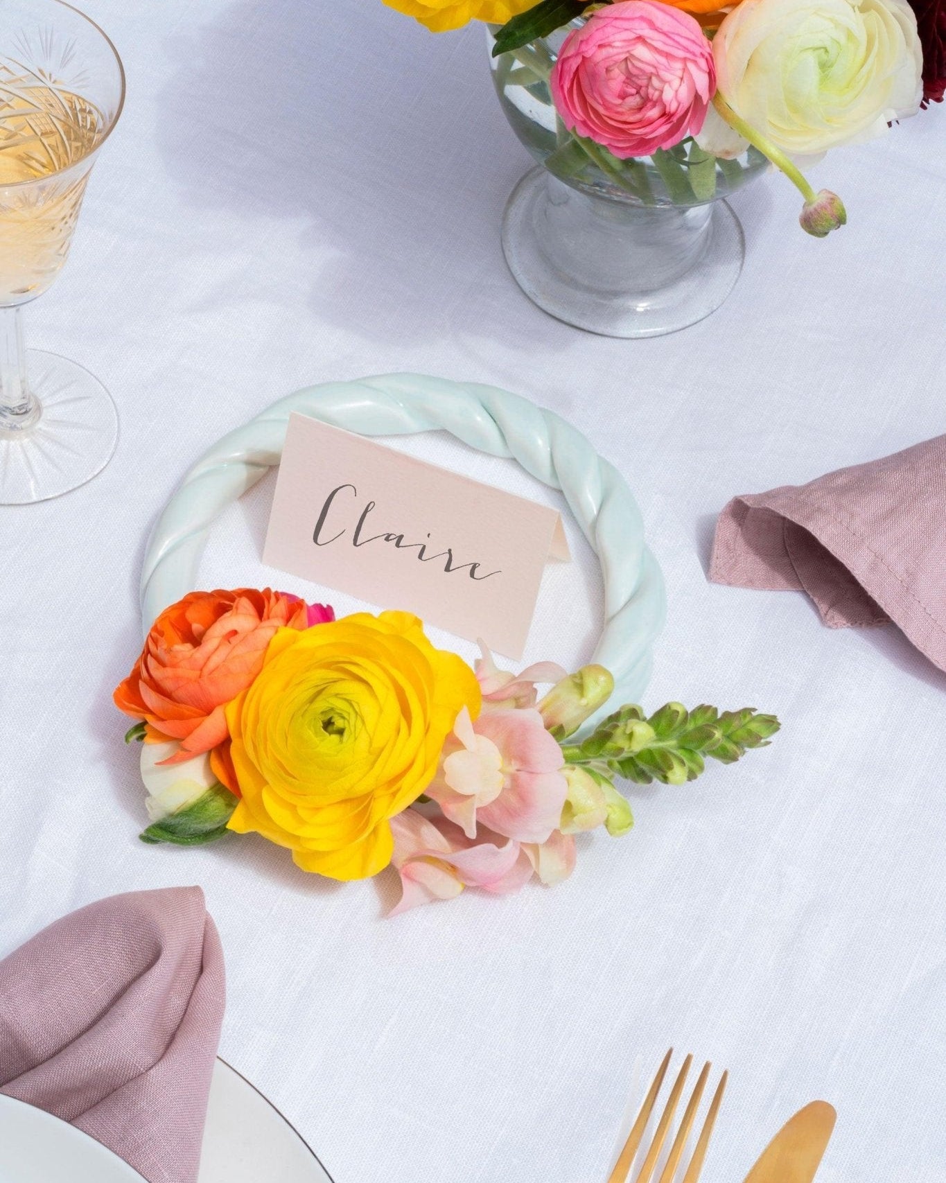 A place card reading Claire with bright flowers, gold cutlery, and the light mint OCTAEVO Sicilia Ceramic Trivet as table decor.