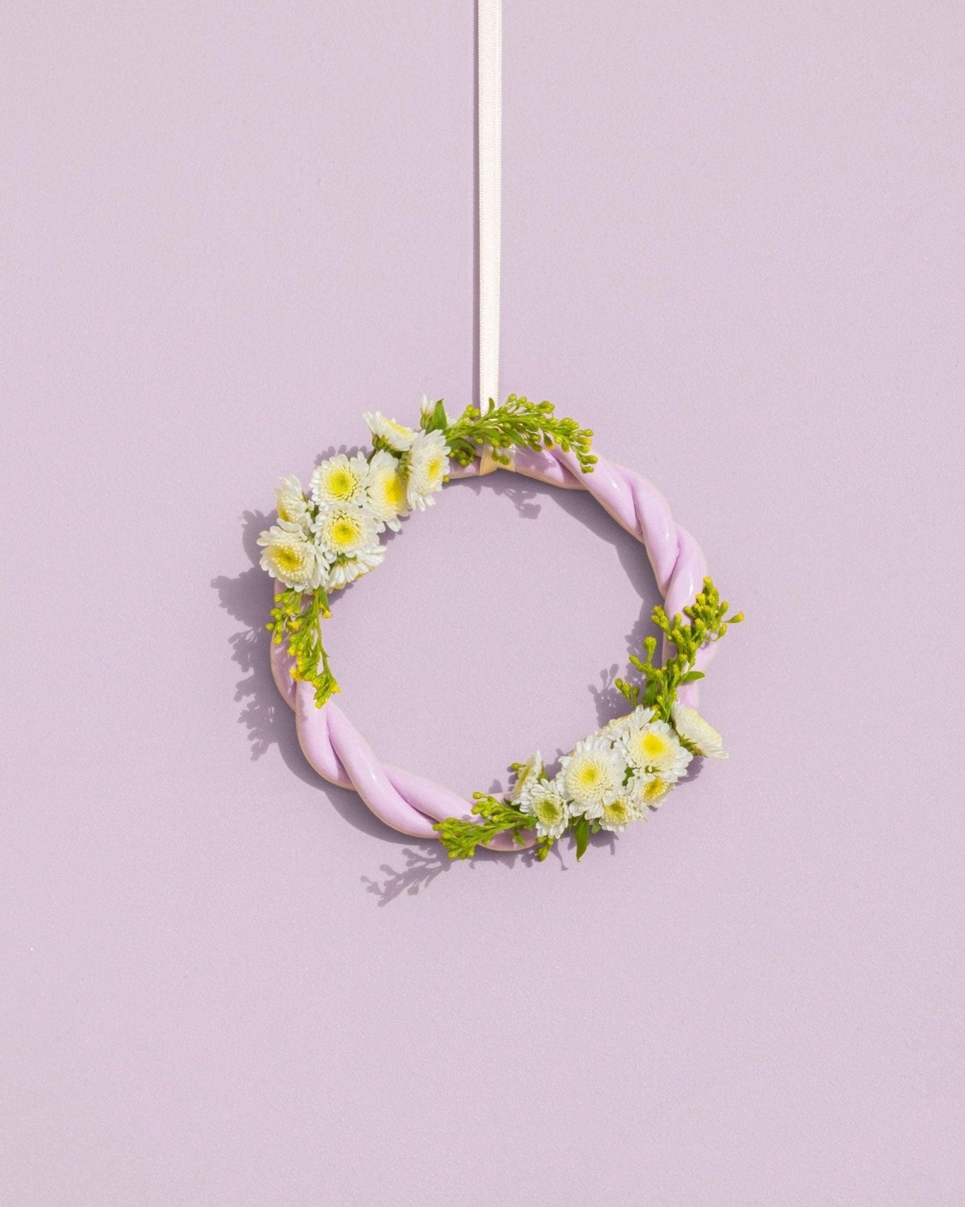 The purple OCTAEVO Sicilia Ceramic Trivet is displayed on a wall, adding a decorative pastel touch.