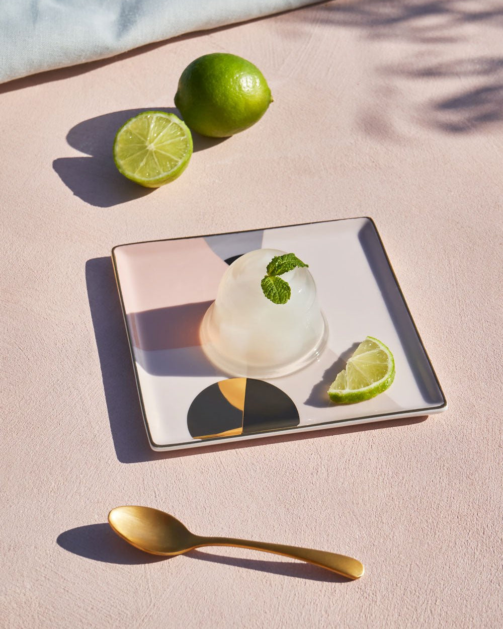 Round dessert with mint and lime on a pink OCTAEVO Siena Ceramic Tray, gold spoon and limes in the background.