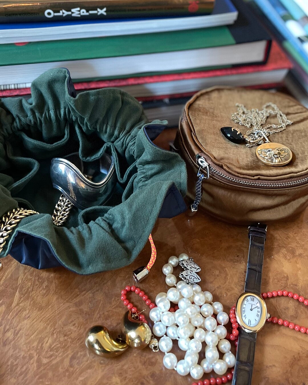 Jewelry and accessories organizers on a wooden surface with books in the background.