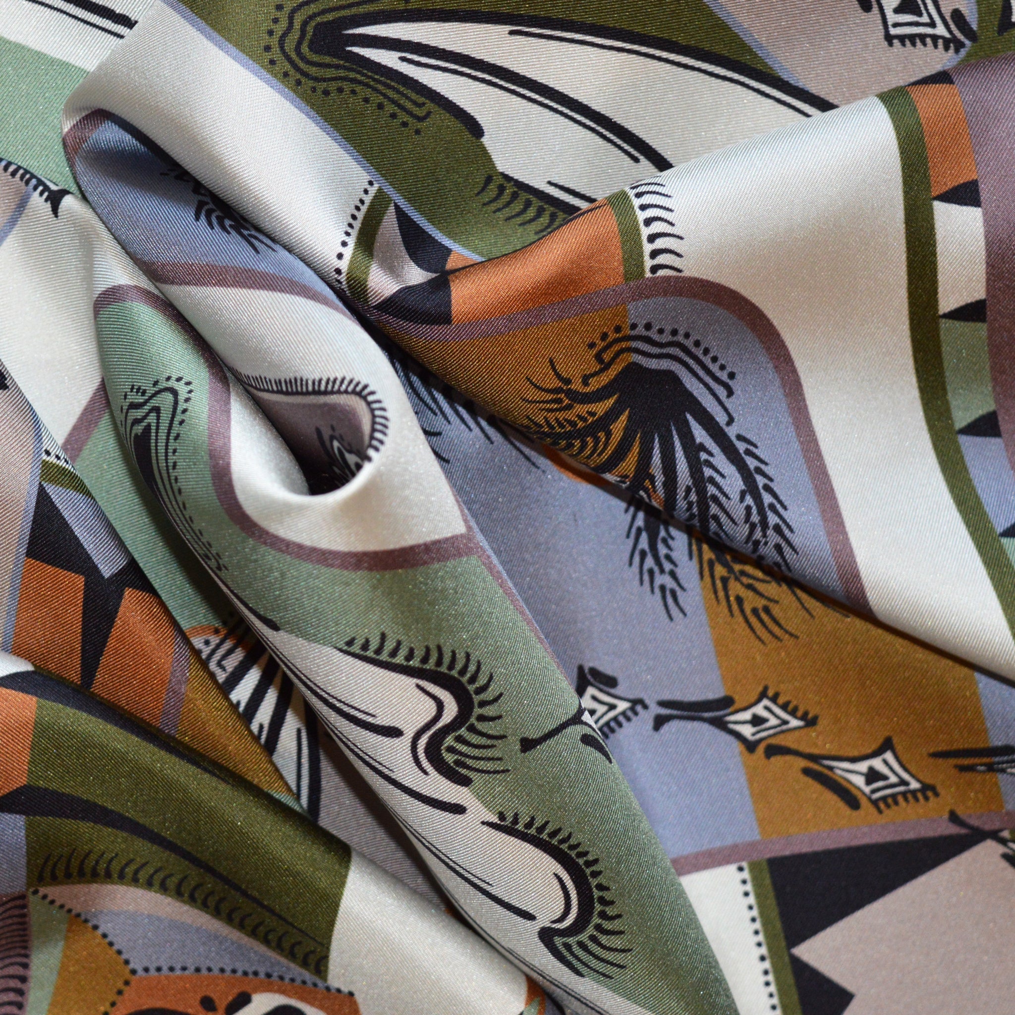 vista ingrandita di un particolare di foulard carré con pattern di piante e bordo geometrico multicolor