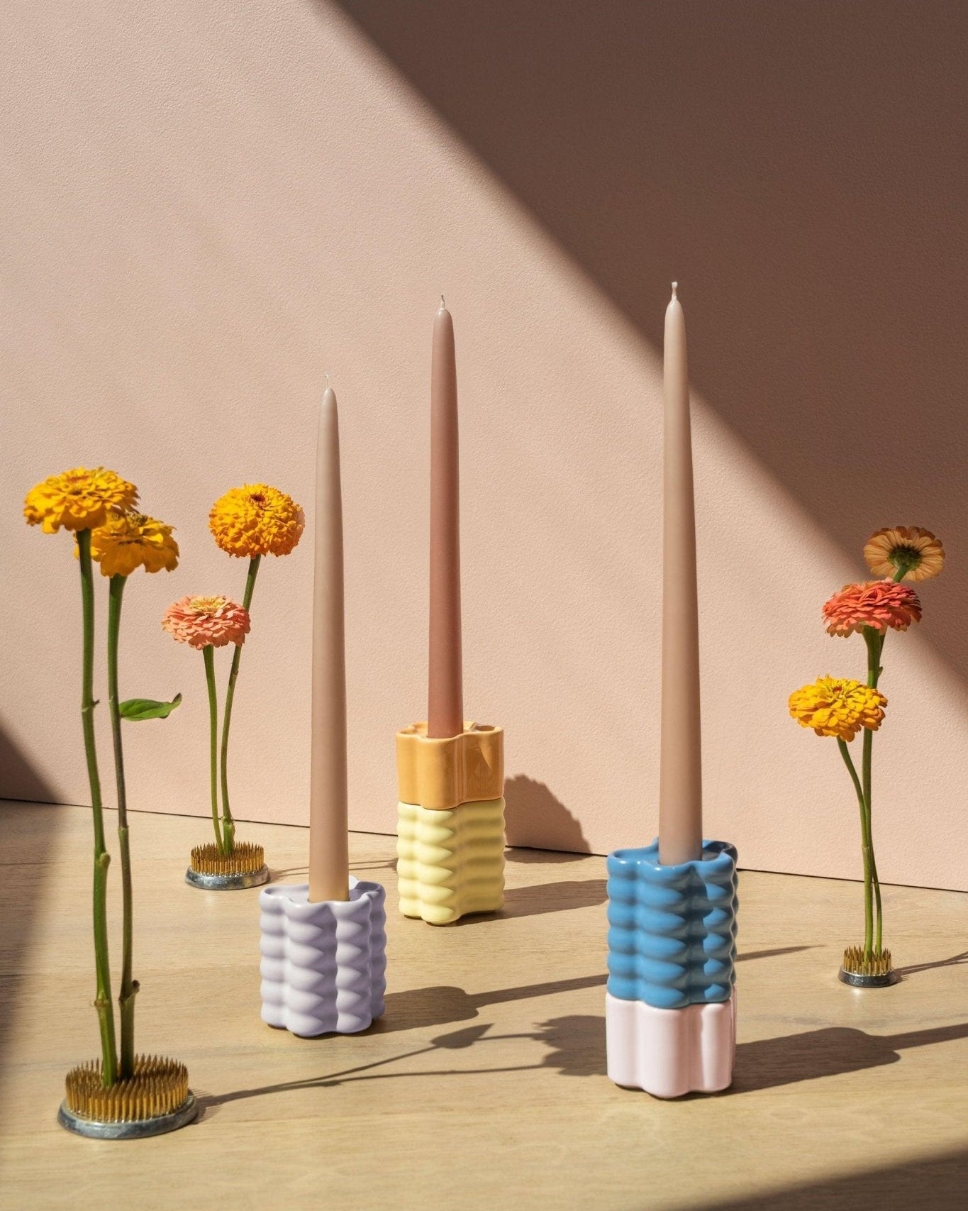 Three pastel ribbed flora holders with taper candles, surrounded by flowers in metal pin holders.