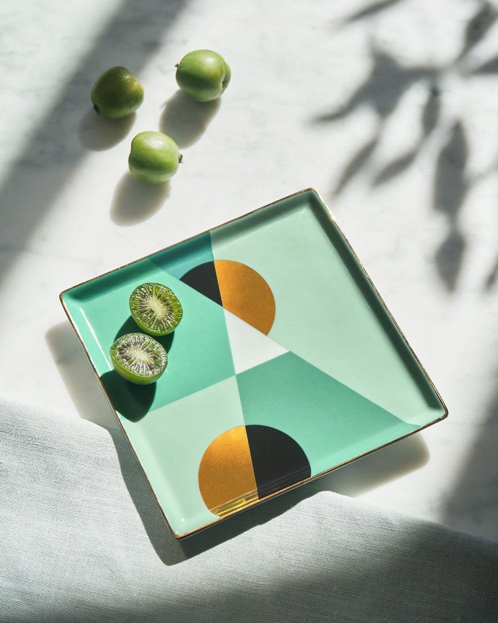 The mint OCTAEVO Siena Ceramic Tray displays two halve fruits and three whole ones on a light surface.
