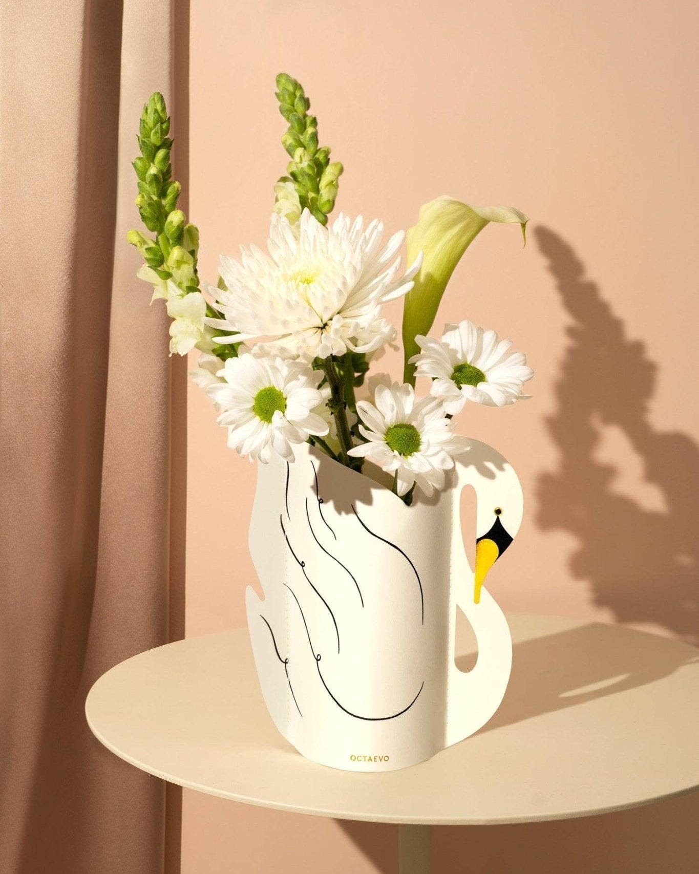 Octaevos Swan Mini Paper Vase holds white blooms and greenery, adding a surreal art touch to your round table.